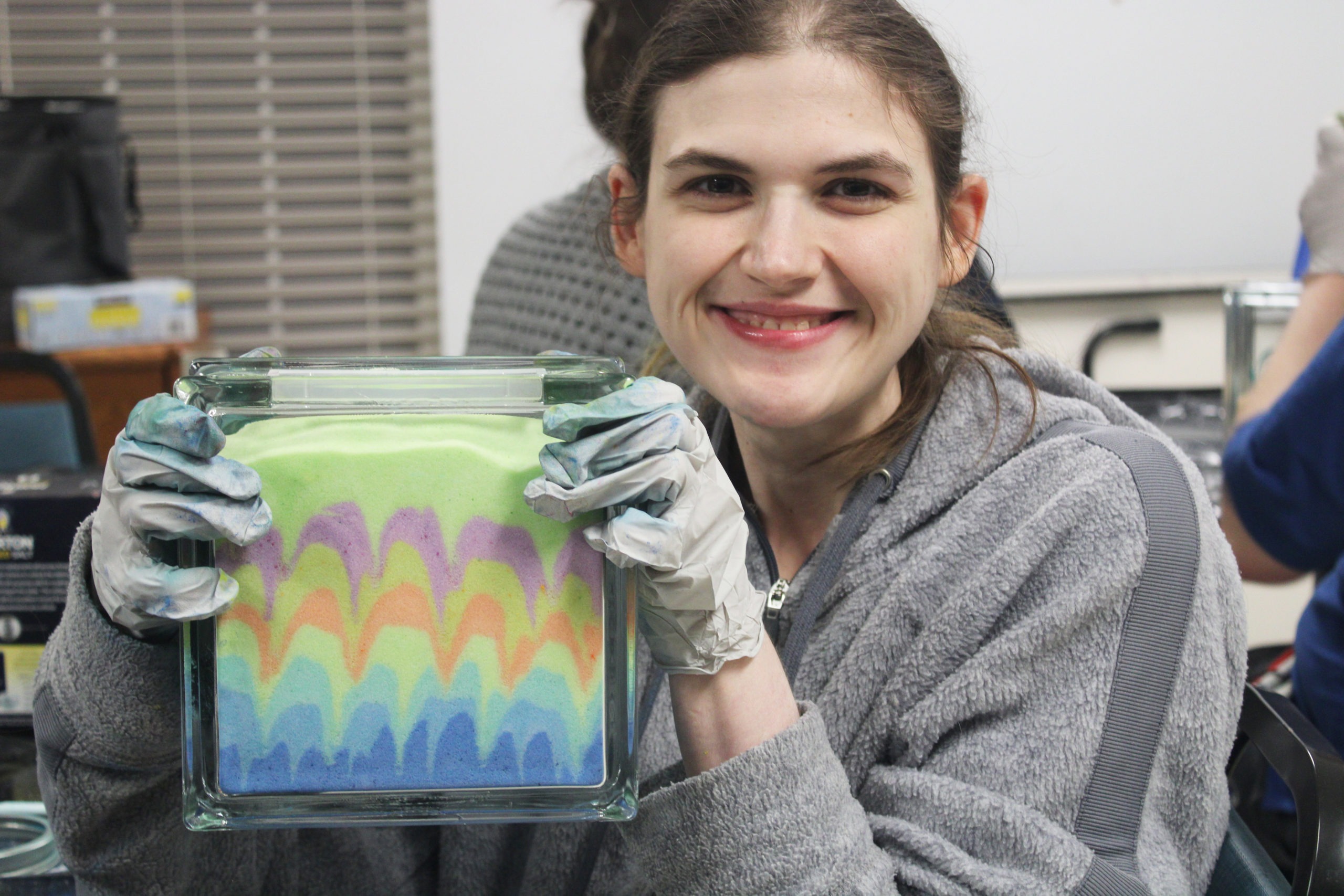 Karinne holding up a block of sand art