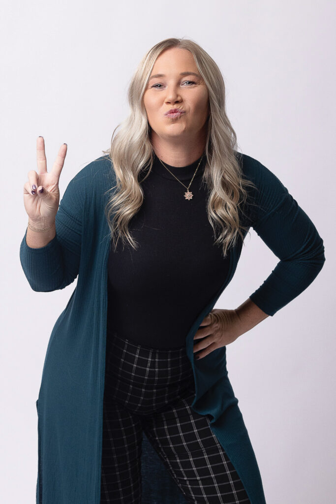 Brittney Moss standing with her hand on her hip and making a peace sign with her fingers