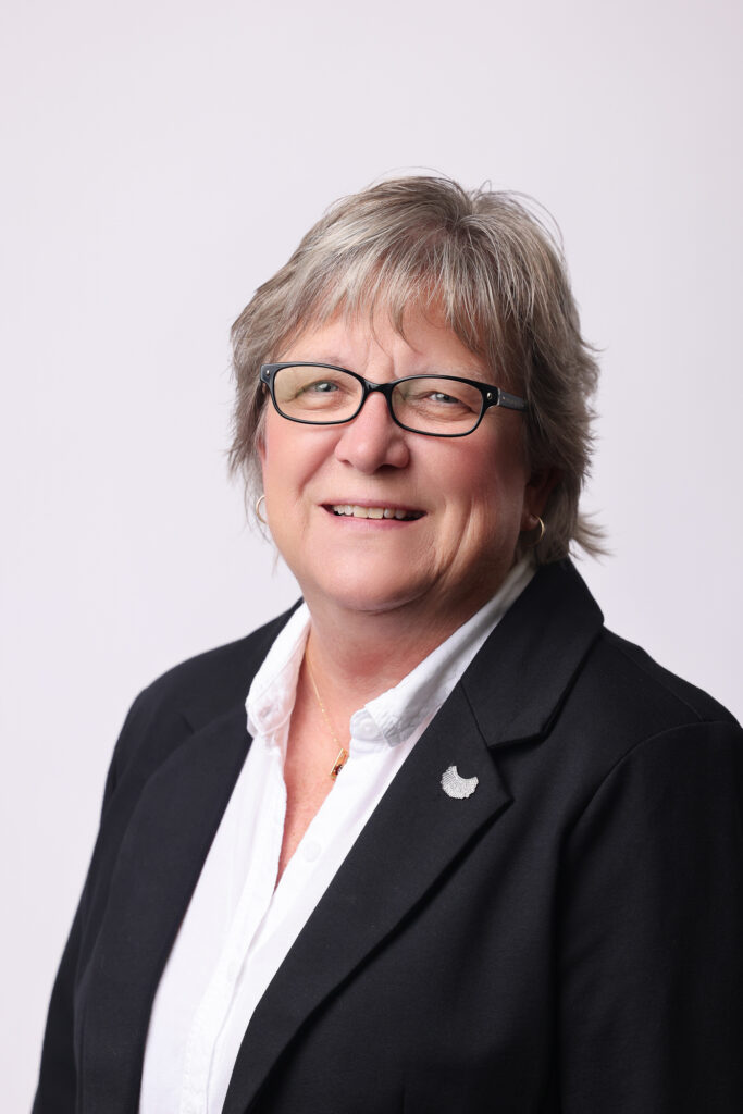 Sheri Wiltse smiling and wearing a white shirt and black jacket