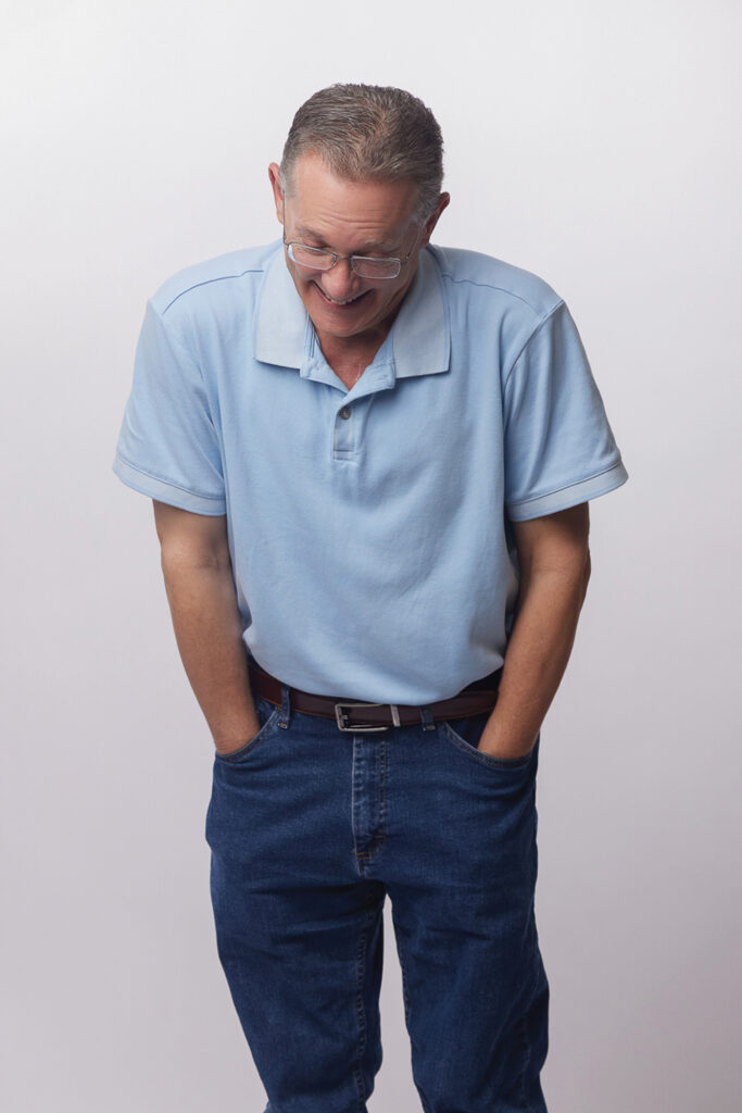 John Ditch standing with his hands in his pockets, smiling and looking down