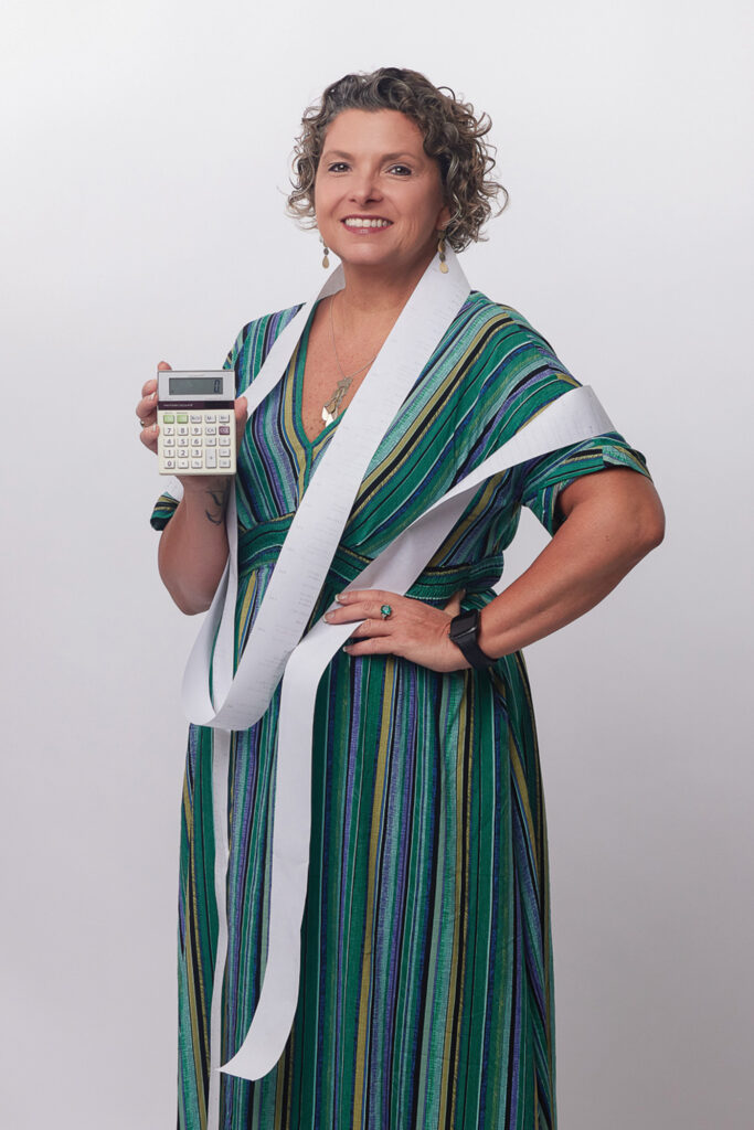 Molly Maher with receipt tape wrapped around her shoulders, holding a calculator