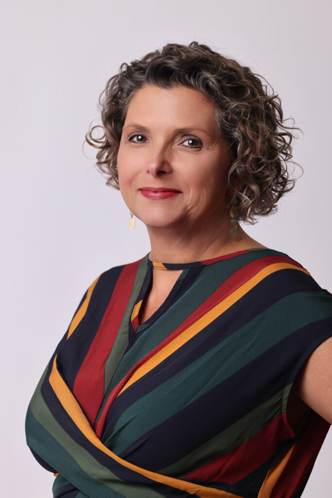 Molly Maher wearing a striped top, smiling against a blank background