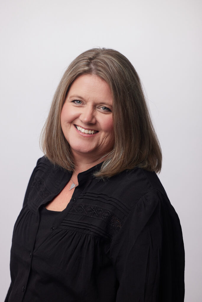 Cathi Bornhop wearing a black top and smiling against a blank background