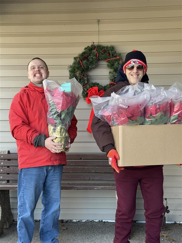 f5dba902-1c4a-4d8d-84e5-6541047d4c85 Two men delivering poinsettia plants to a home