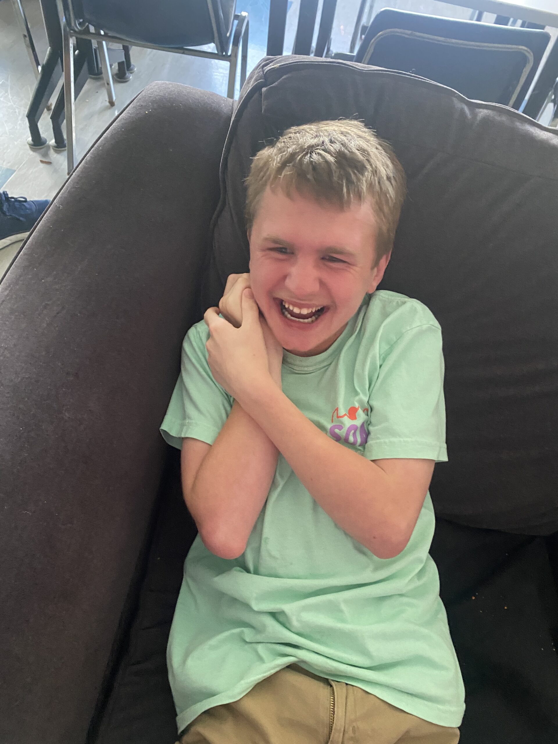 Alex laughs and smiles in an oversized chair.