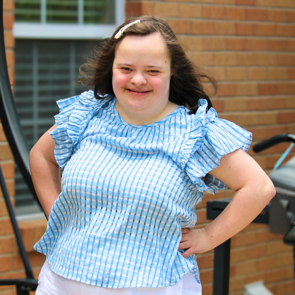 Paticipant smiling and posing with hands on her hips outside of a brick building.