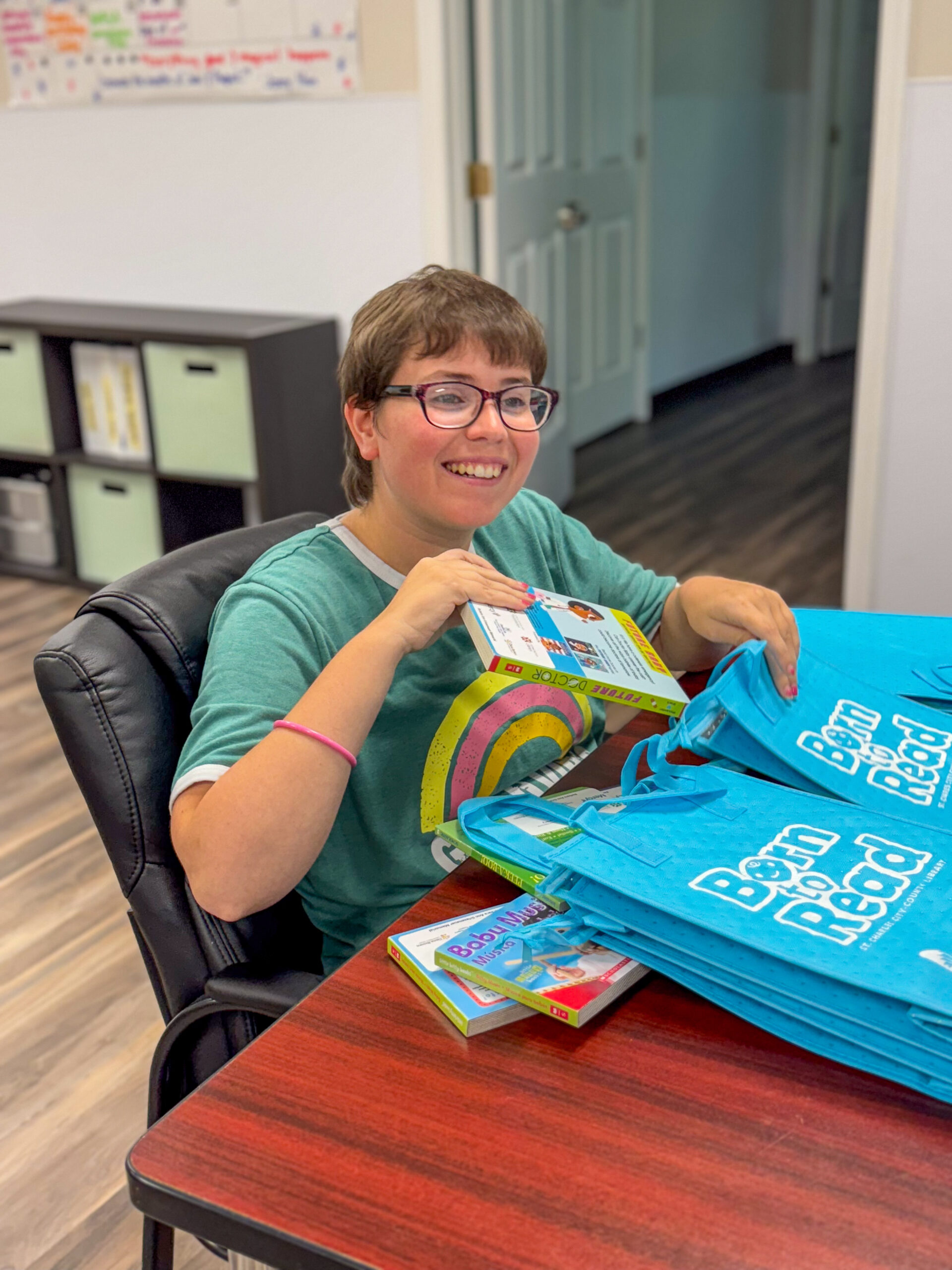 Allison sits at a table and puts a book inside a blue bag